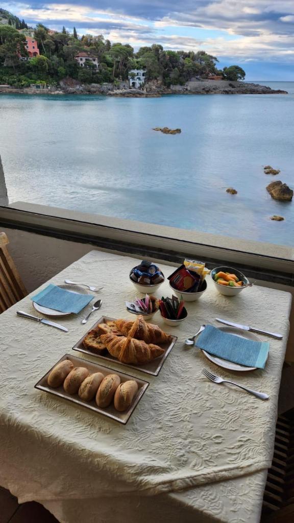 une table avec de la nourriture dessus avec vue sur l'eau dans l'établissement Locanda Il Senatore, à Fiascherino