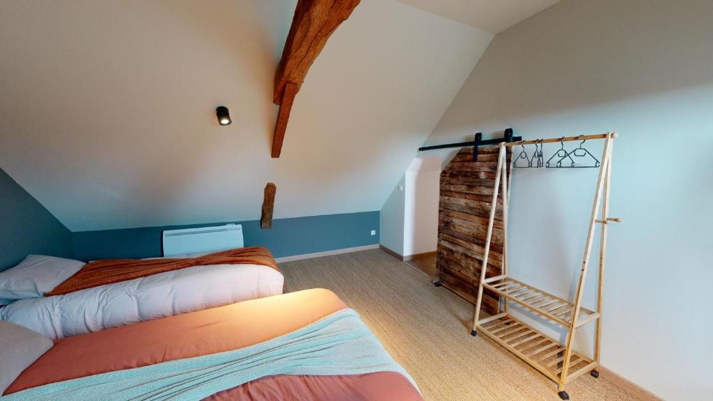 Cette chambre mansardée comprend 2 lits et un miroir. dans l'établissement Les Grands Ormeaux - Elégance & Piscine chauffée - L'Instant Clef, à Joué-en-Charnie 37 autres photos