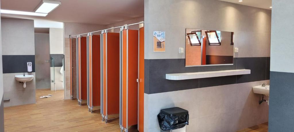 La salle de bains est pourvue d'une rangée de stalles avec des panneaux orange. dans l'établissement Chalet Coco, à Roquebrune-sur Argens