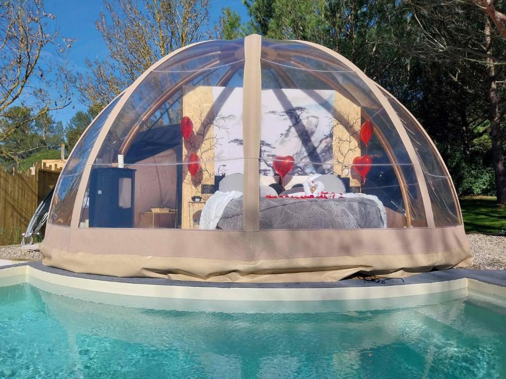 une tente au-dessus d'une piscine avec un lit dans l'établissement Le Clos FMR Insolite - "F"anny Carcassonne, à Malves