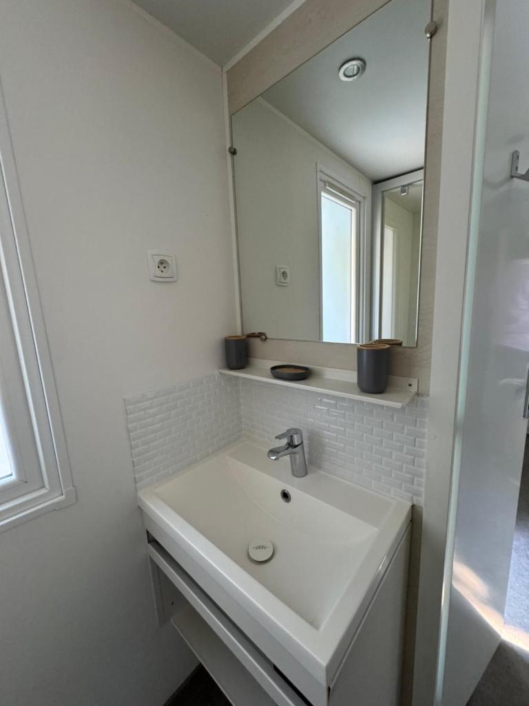 une salle de bain blanche avec un lavabo et un miroir dans l'établissement Chez Flo Mobil-Home H13, à Gassin