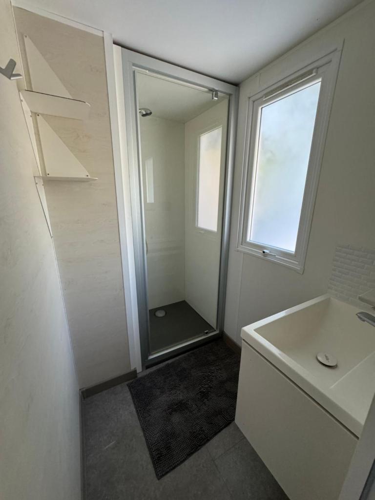 une salle de bain avec une douche, un lavabo et un miroir dans l'établissement Chez Flo Mobil-Home H13, à Gassin 4 autres photos
