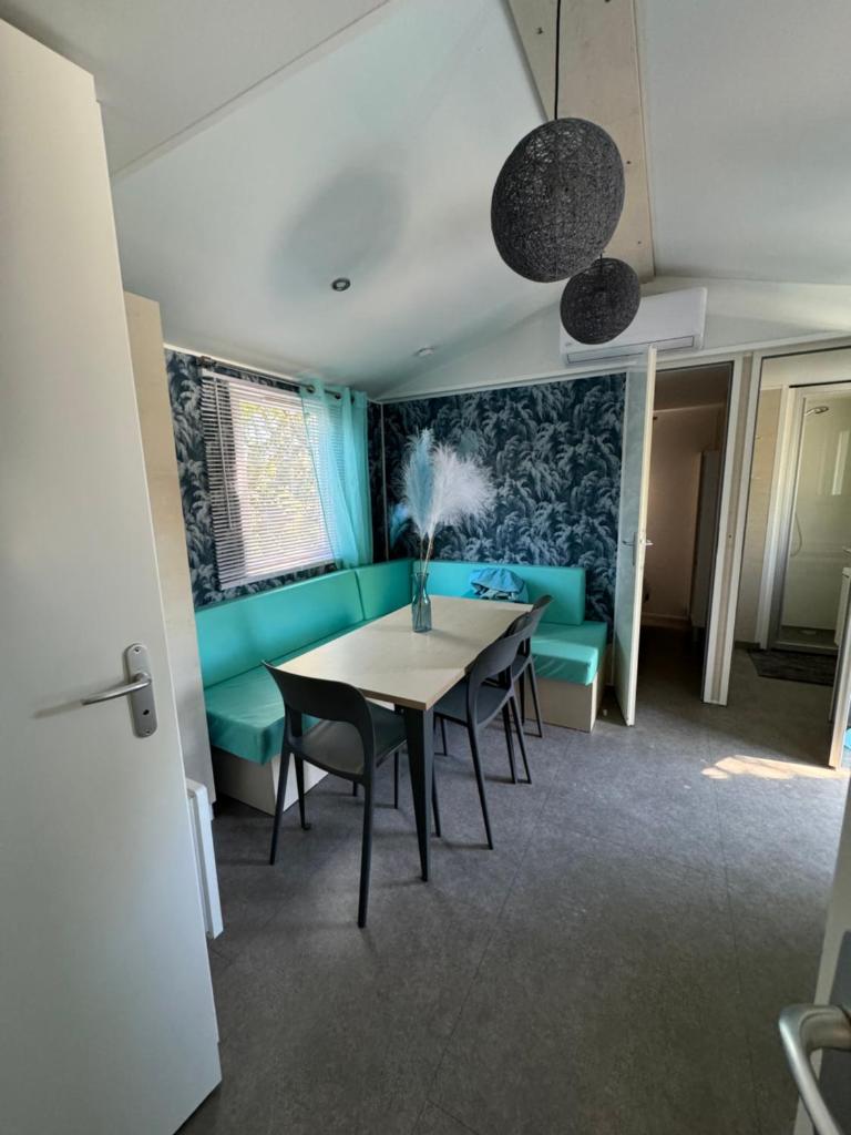 une salle à manger avec une table et un canapé bleu dans l'établissement Chez Flo Mobil-Home H13, à Gassin