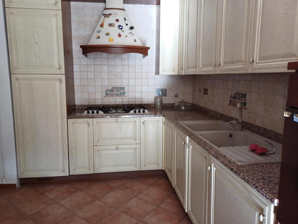 une cuisine avec des armoires blanches et un évier dans l'établissement Max House, à Marina di Cerveteri