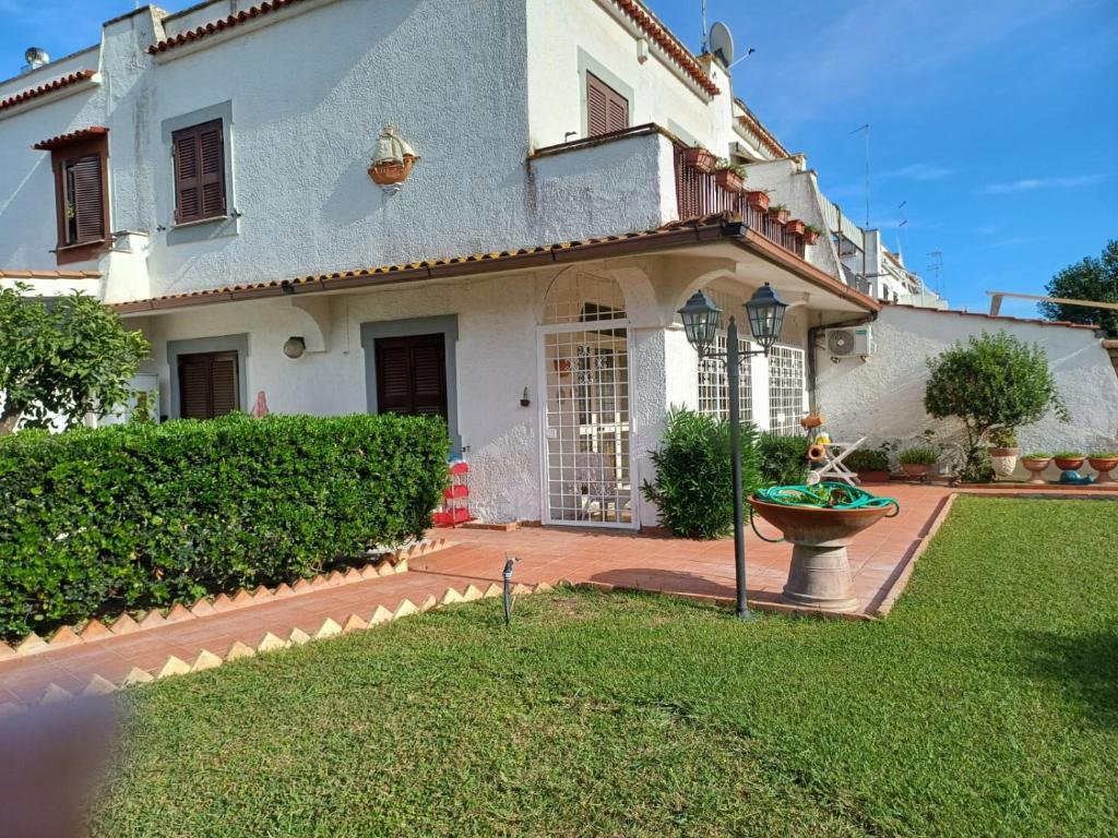 Une grande maison blanche avec une fontaine dans la cour dans l'établissement Max House, à Marina di Cerveteri
