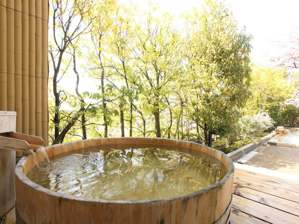 une baignoire en bois remplie d'eau sur une terrasse dans l'établissement Yuzanso, à Ōtsu 37 autres photos