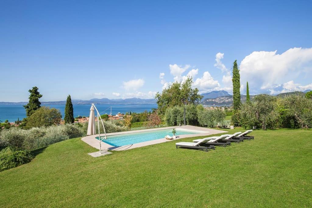 - une piscine entourée d'une pelouse avec des chaises longues dans l'établissement Villa Golden Suite - Bardolino Verona, à Bardolino