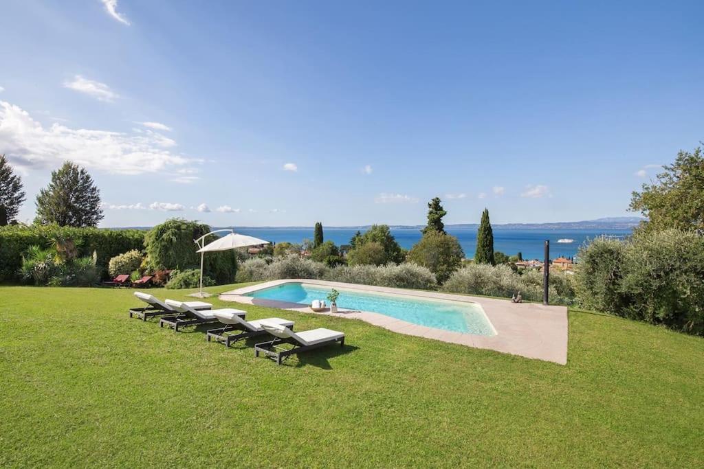 - une piscine avec des chaises longues dans une pelouse dans l'établissement Villa Golden Suite - Bardolino Verona, à Bardolino