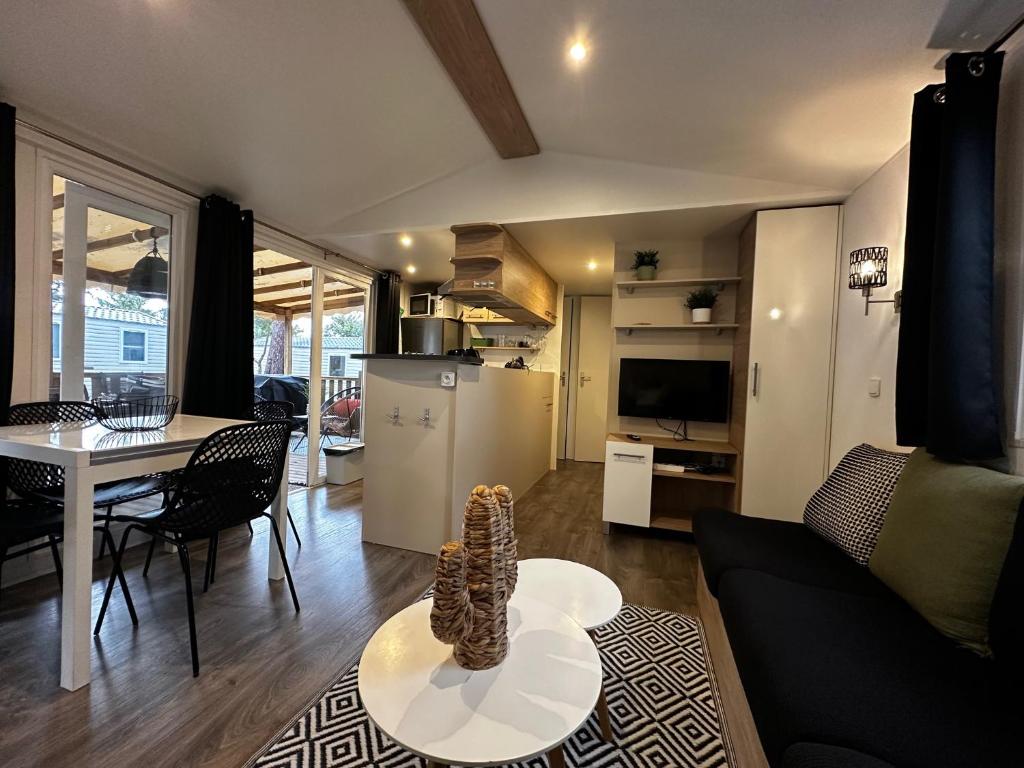 un salon avec un canapé et une table et une cuisine dans l'établissement Grand Mobil Home Tout Confort pour 6 personnes - Camping Les Oyats 4 étoiles, à Seignosse