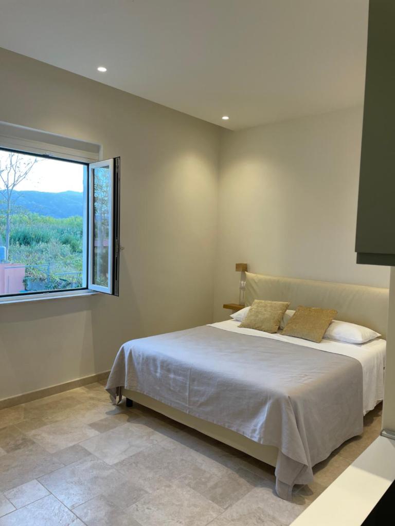 une chambre avec un lit et une grande fenêtre dans l'établissement Villa Achiropita, à Rossano