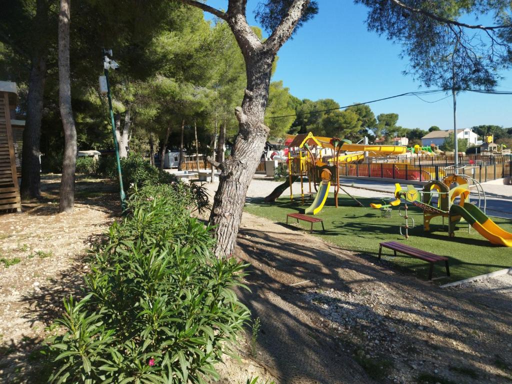 un parc avec une aire de jeux avec des toboggans et un arbre dans l'établissement MOBIL HOME Neuf FRONT DE MER TOUT CONFORT 5 LITS 6 personnes CARRY LE ROUET, à Carry-le-Rouet