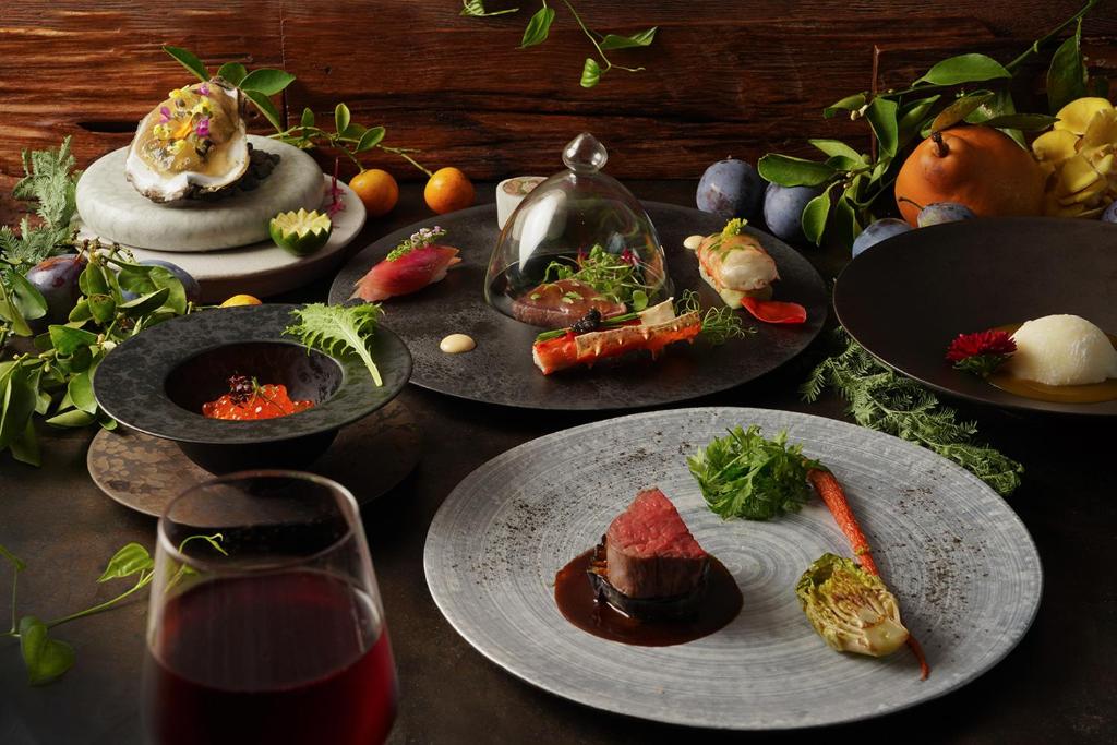 une table avec des assiettes de nourriture et un verre de vin dans l'établissement Nasu-Onsen Shinshun no Kago Hewitt Resort, à Nasu 31 autres photos