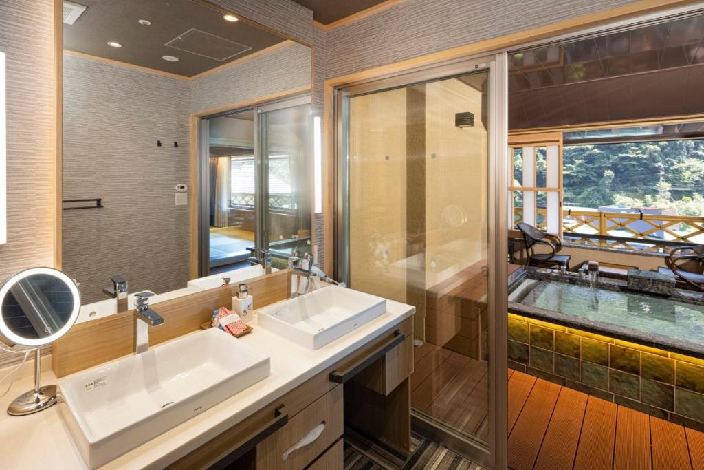 une salle de bain avec deux lavabos et un grand miroir dans l'établissement Hotel Okada, à Hakone