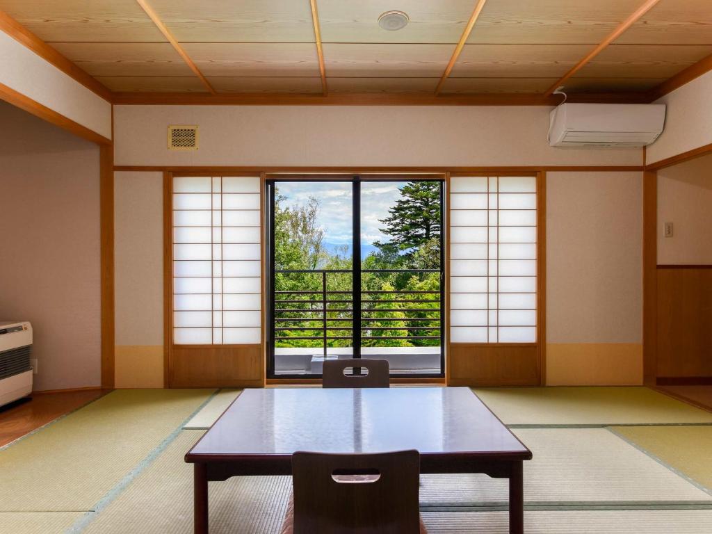 une pièce avec une table et une grande fenêtre dans l'établissement Suzuranso, à Komagane