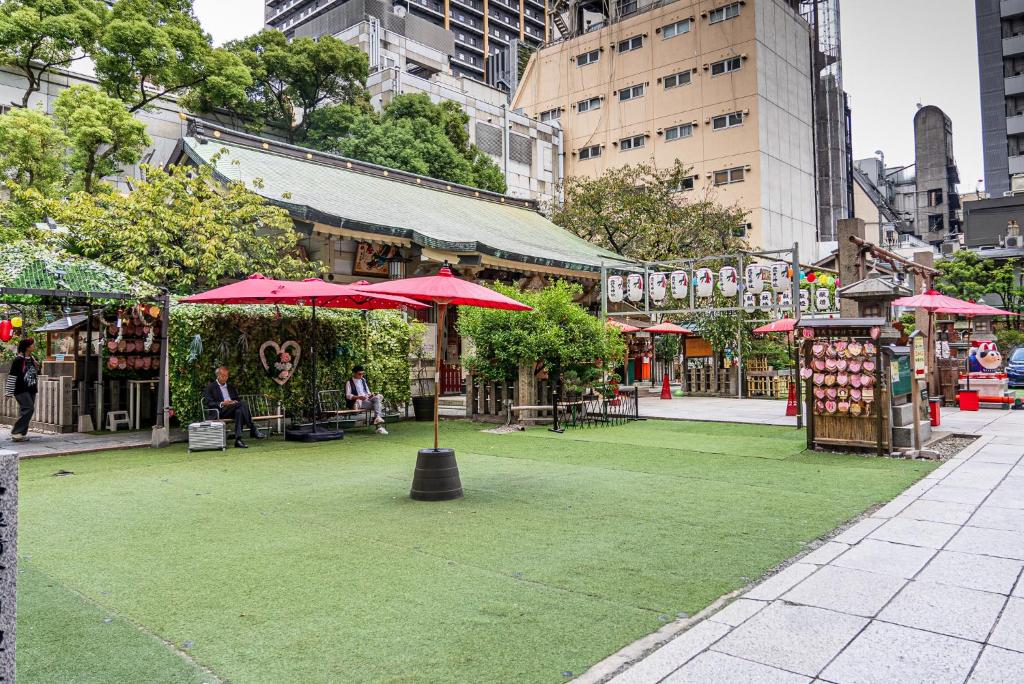 un espace vert avec des parapluies rouges dans une rue de la ville dans l'établissement Hotel Salle de bain, à Osaka