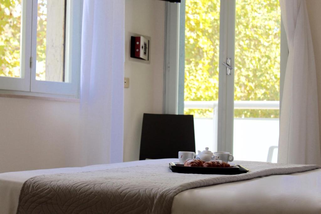une assiette de nourriture sur un lit avec une fenêtre dans l'établissement Roi Hotel, à Cesenatico