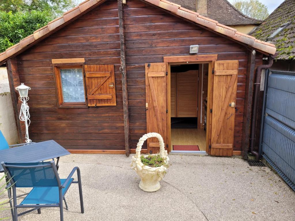 un hangar en bois avec une porte, une table et une chaise dans l'établissement Au petit Chalet, à Gigouzac