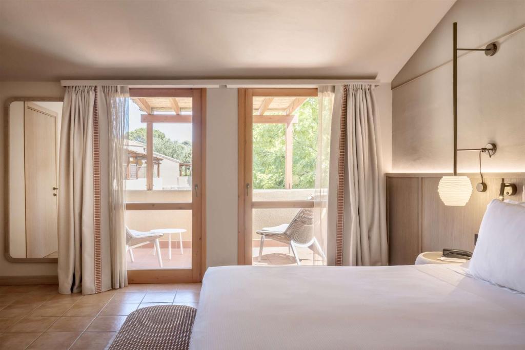 une chambre avec un grand lit et un balcon dans l'établissement Veridia Resort Sardinia, a member of Radisson Individuals, à Chia