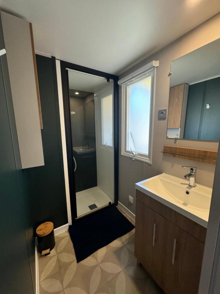 une salle de bain avec une douche, un lavabo et un miroir dans l'établissement Mobile home 255 pour 6 pers Camping Siblu Le Lac des Rêves, à Lattes