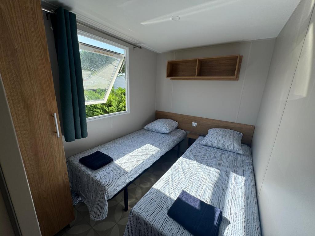 une petite chambre avec deux lits et une fenêtre dans l'établissement Mobile home 255 pour 6 pers Camping Siblu Le Lac des Rêves, à Lattes