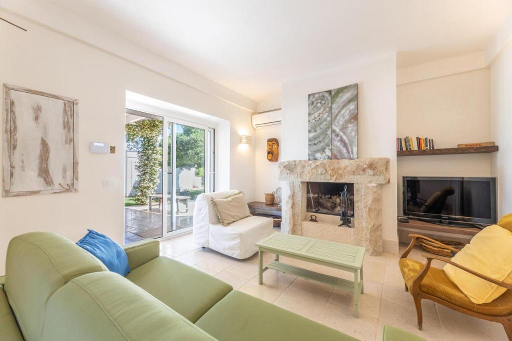 - un salon avec un canapé vert et une cheminée dans l'établissement Villa con Piscina e Jacuzzi privata - 3 minuti dal mare, à Specchiolla