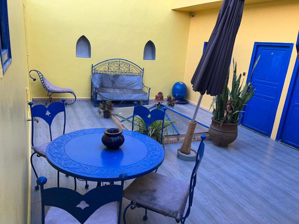 un patio avec une table, des chaises et un lit dans l'établissement Riad Le Lieu, à Tiznit