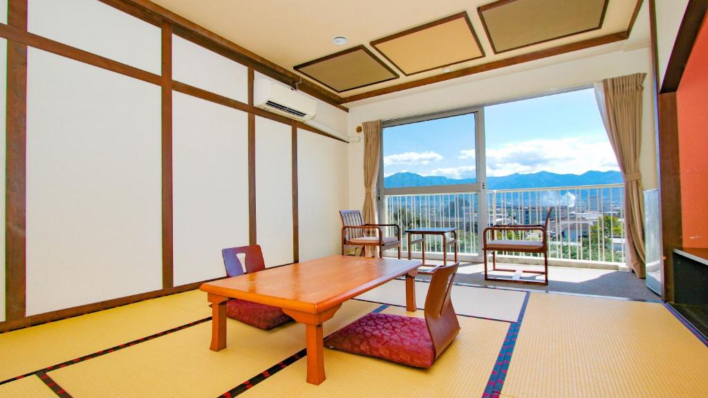une pièce avec une table et des chaises et une grande fenêtre dans l'établissement Ooedo Onsen Monogatari Hotel Shinko, à Fuefuki