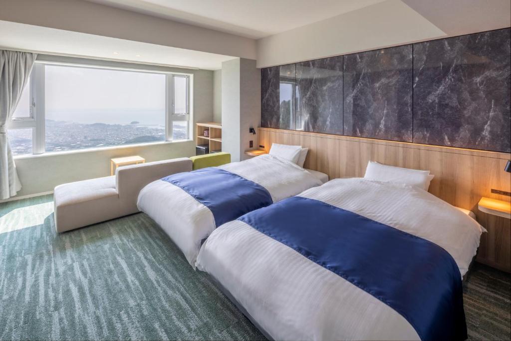 deux lits dans une chambre avec une grande fenêtre dans l'établissement Tennomaru, à Gamagori 37 autres photos