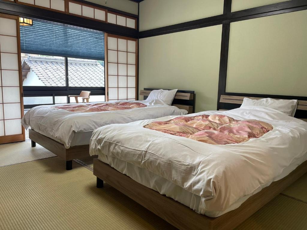 deux lits dans une chambre avec deux fenêtres dans l'établissement 湯宿ささくら, à Kinosaki