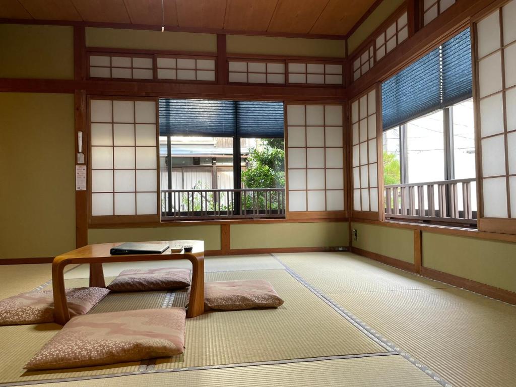 une chambre avec une table et trois fenêtres dans l'établissement 湯宿ささくら, à Kinosaki
