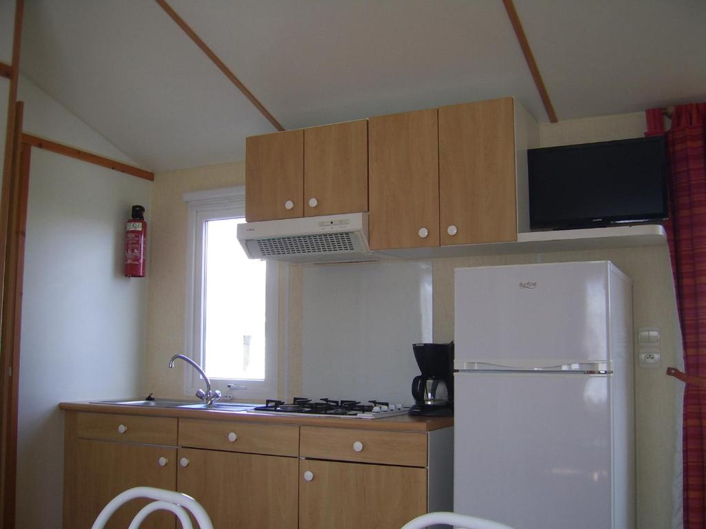 La cuisine est équipée d'un réfrigérateur blanc et d'un four micro-ondes. dans l'établissement Mobil-home 1 chambre 2 personnes à 15 min des Sables d'Olonne, à Vairé 22 autres photos