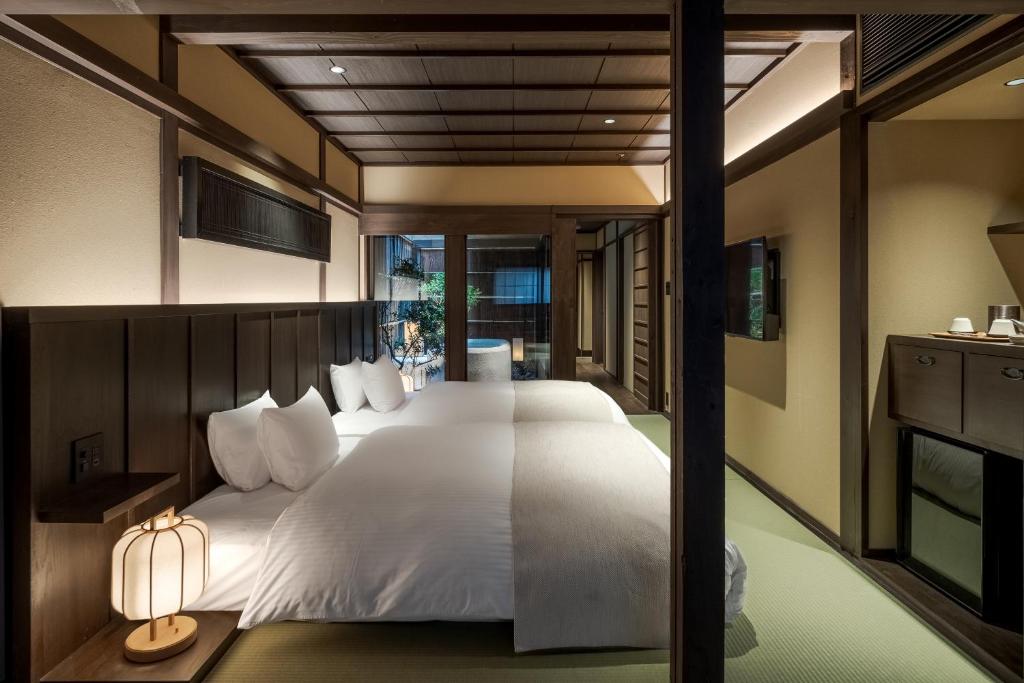 une chambre avec un grand lit avec des draps blancs dans l'établissement Nazuna Kyoto Higashi Honganji, à Kyoto