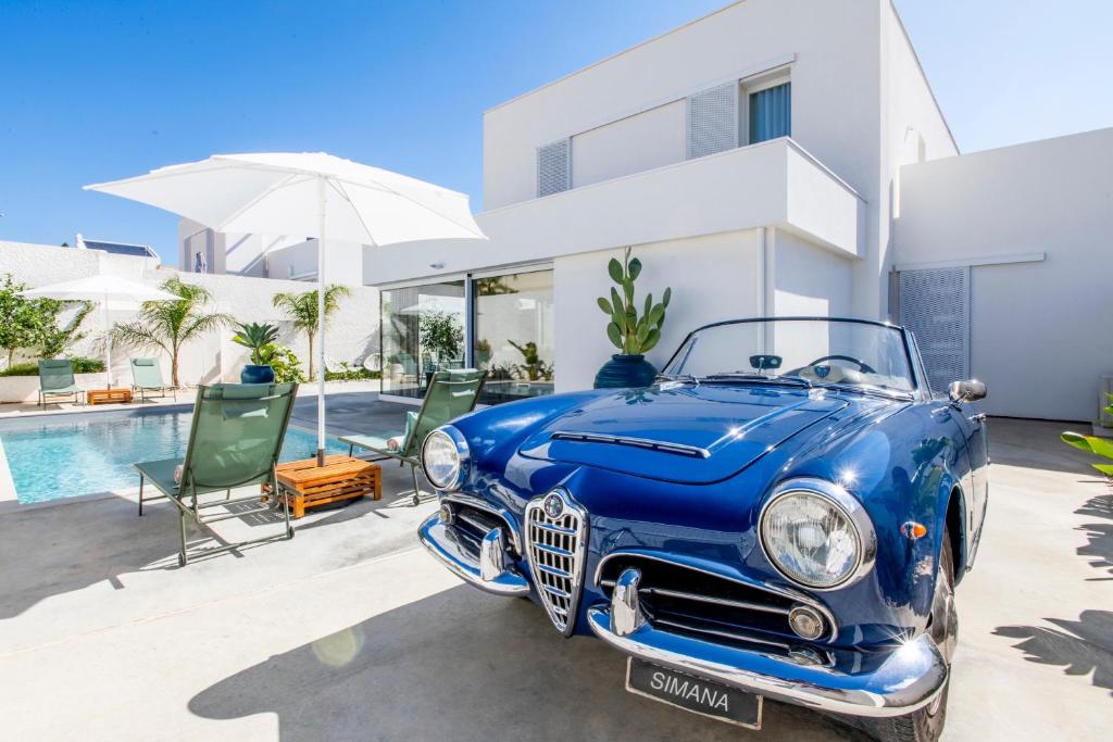 une vieille voiture bleue garée devant une maison dans l'établissement SIMANA Mediterranean Pool Villas, à Marina di Ragusa