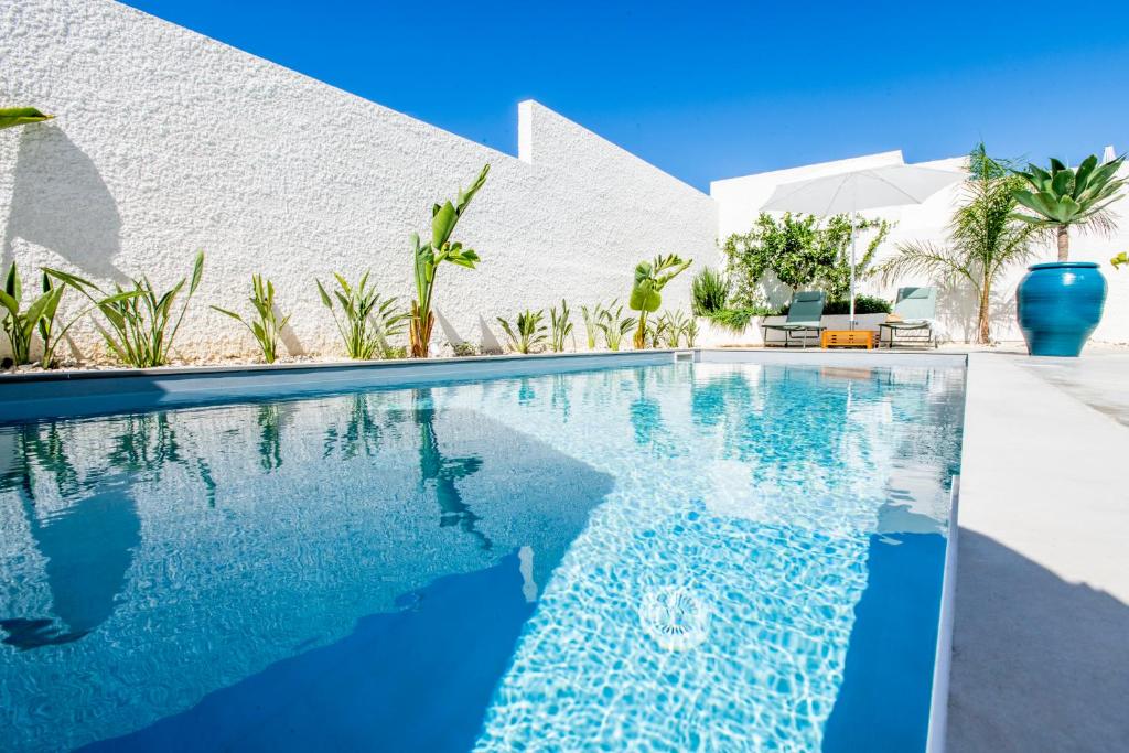une piscine devant une maison blanche dans l'établissement SIMANA Mediterranean Pool Villas, à Marina di Ragusa