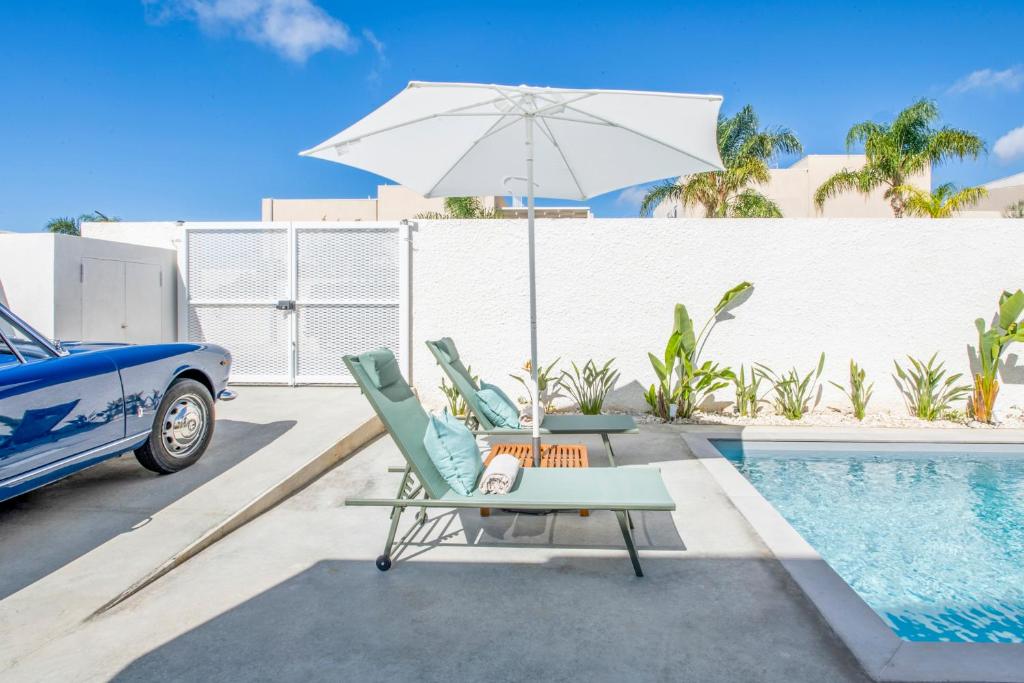 une paire de chaises et un parasol à côté d'une piscine dans l'établissement SIMANA Mediterranean Pool Villas, à Marina di Ragusa