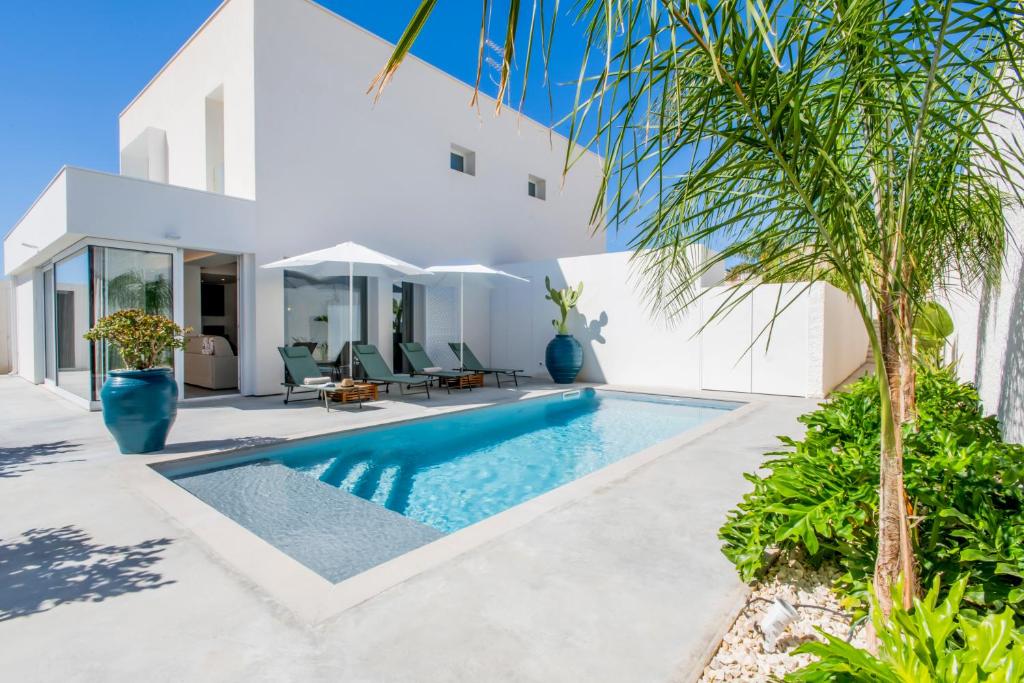 - une piscine dans l'arrière-cour d'une maison avec une villa dans l'établissement SIMANA Mediterranean Pool Villas, à Marina di Ragusa