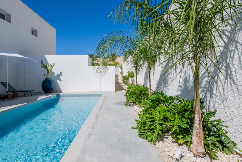 une piscine avec des palmiers à côté d'un immeuble dans l'établissement SIMANA Mediterranean Pool Villas, à Marina di Ragusa 39 autres photos