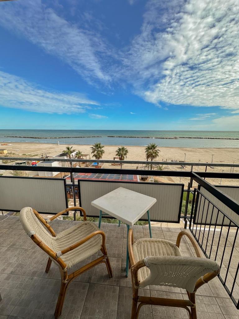 une table et des chaises sur un balcon avec la plage dans l'établissement Hotel Re Leone, à Rimini