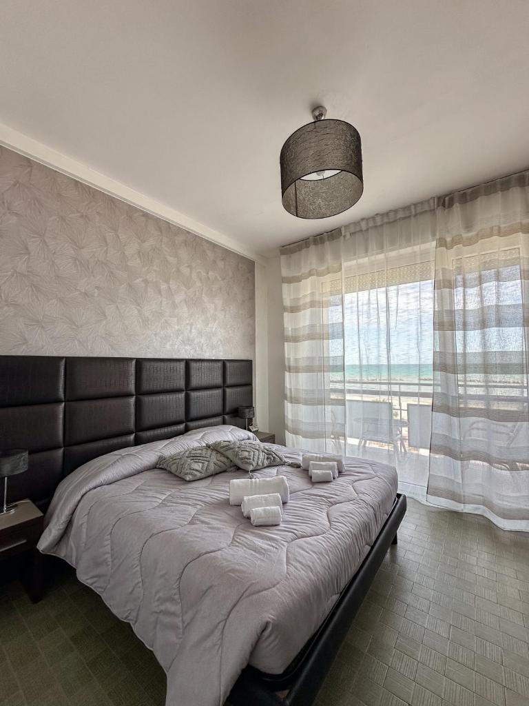 une chambre avec un grand lit avec une grande fenêtre dans l'établissement Hotel Re Leone, à Rimini