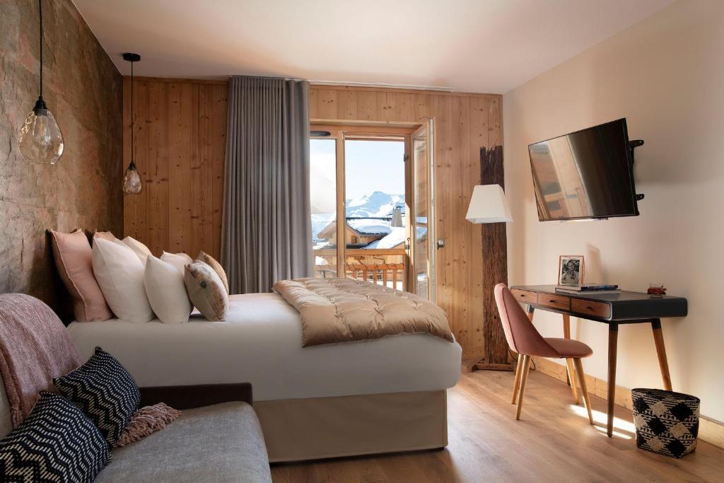 - une chambre avec un lit, un bureau et une télévision dans l'établissement Grandes Rousses Hotel & Spa, à L'Alpe-d'Huez