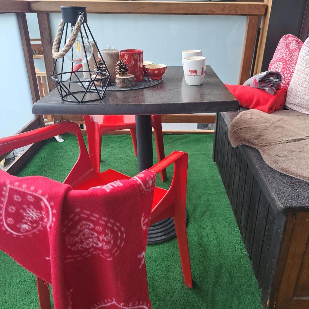 - une table et deux chaises rouges dans le salon dans l'établissement STUDIO 2 ALPES STYLE CHALET au PIED DE TELESIEGE DU DIABLE, à Les Deux Alpes