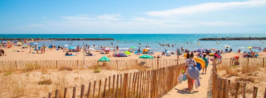Une foule de gens sur une plage avec l'océan dans l'établissement Mobil-Home La Carabasse, à Vias