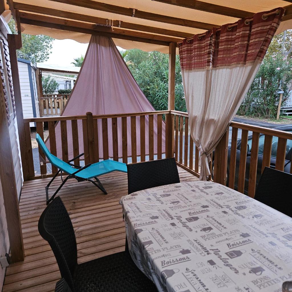une terrasse couverte avec une table, des chaises et une tente dans l'établissement mobilhome, à Valras-Plage