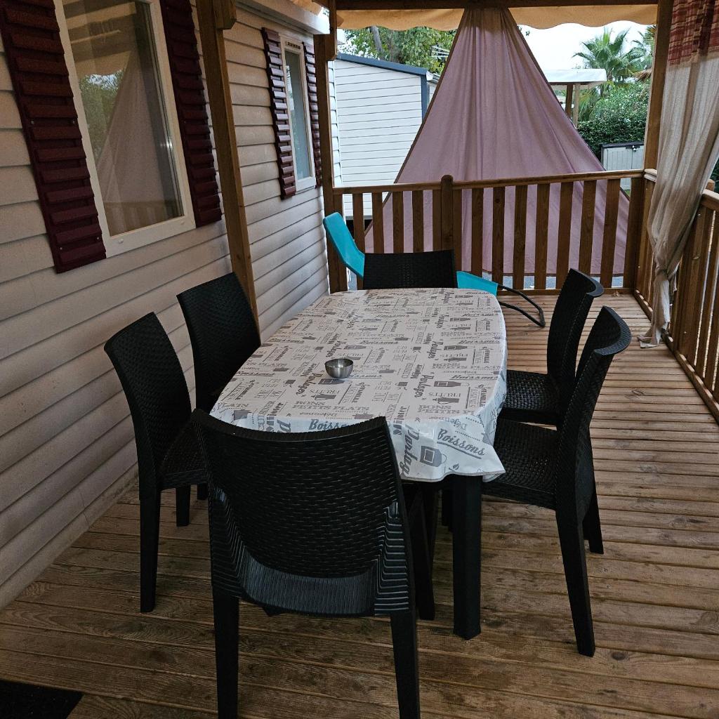 - une table et des chaises sur la terrasse couverte d'une maison dans l'établissement mobilhome, à Valras-Plage