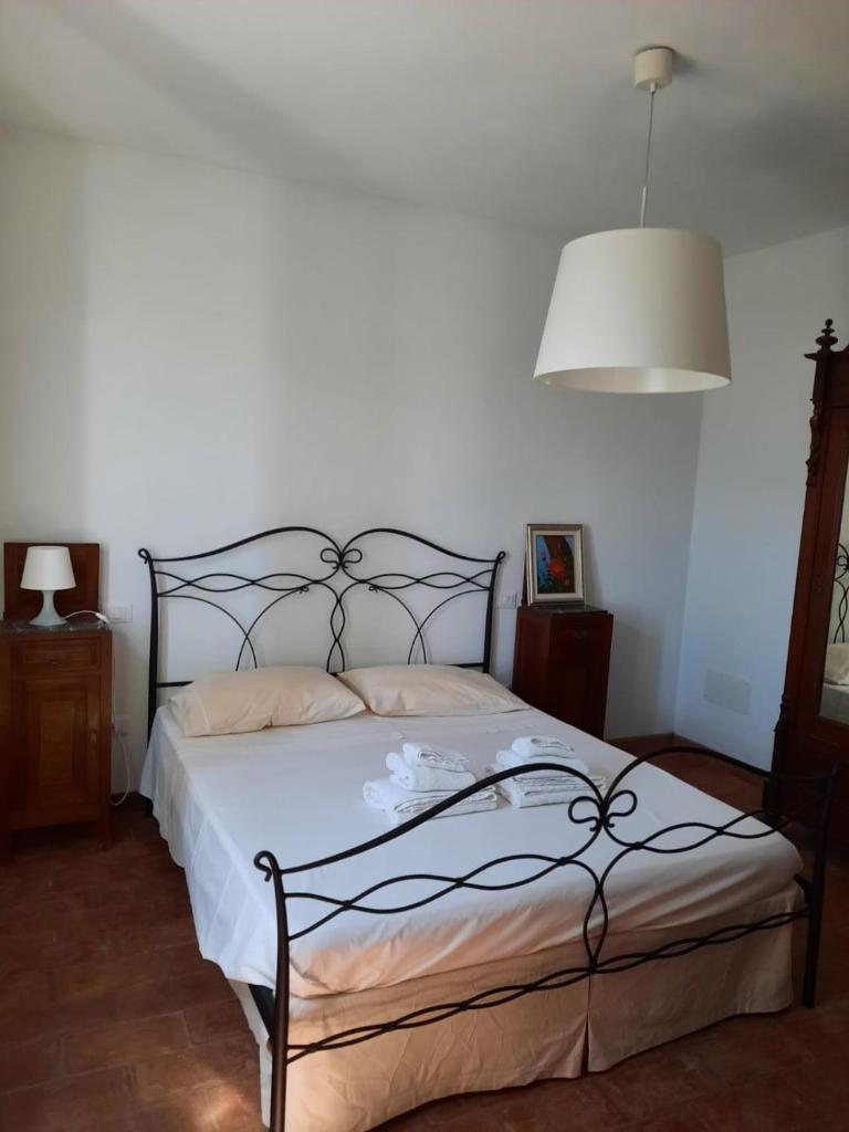 une chambre avec un lit avec des draps blancs et une lampe dans l'établissement Podere San Martino, à Buti