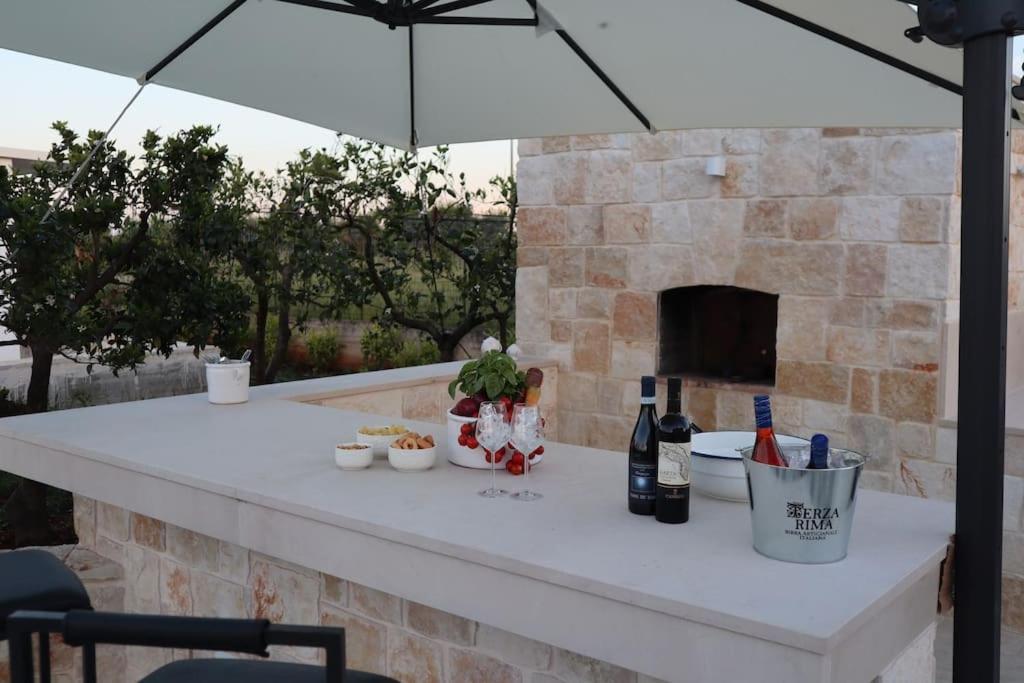 - une table extérieure avec un parasol et une cheminée dans l'établissement Malia Holiday Villa, à Conversano