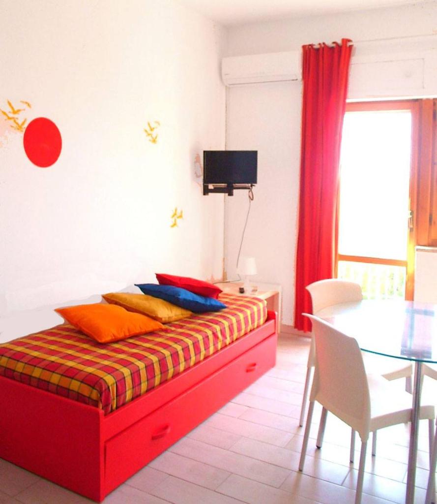 - une chambre avec un lit rouge et des oreillers colorés dans l'établissement Residence La Giungla, à Falerna