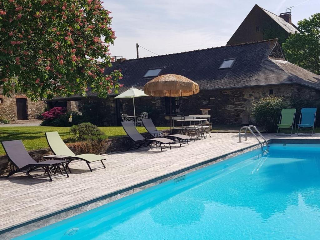 - une piscine avec des chaises, une table et un parasol dans l'établissement Havre de paix avec piscine chauffée, jardin arboré et activités pour tous - FR-1-306-1142, à Teillé