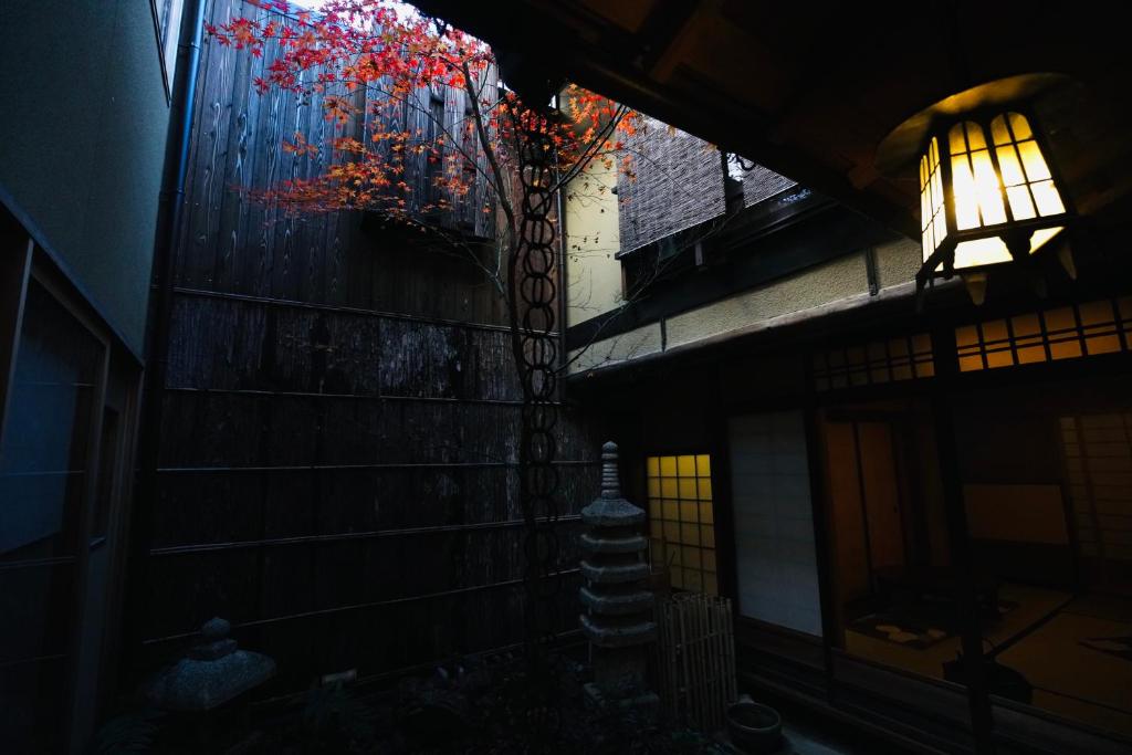 Une allée sombre avec une fenêtre et un arbre avec des feuilles rouges dans l'établissement Ryokan Tori, à Kyoto 37 autres photos