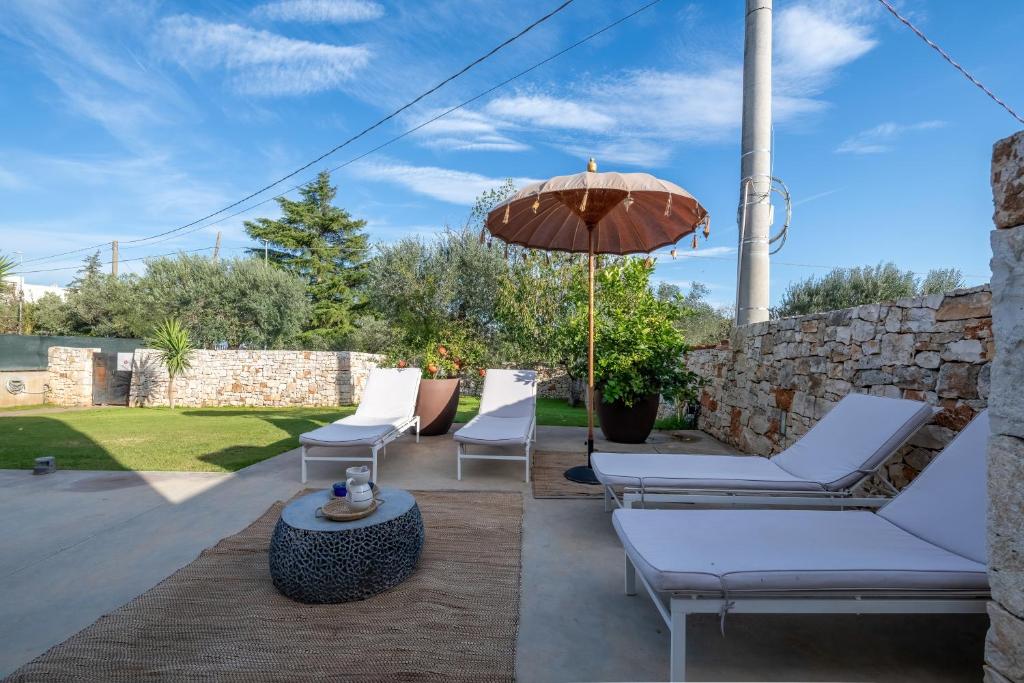 une terrasse avec des chaises blanches et un parasol dans l'établissement Torlevigne Relax & Pool, à Polignano a Mare